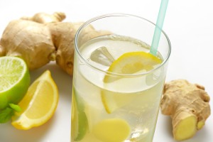 detail of glass of ginger ice tea with lemon and fresh ginger