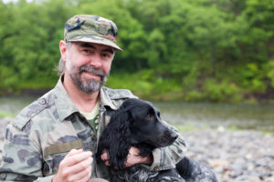 Middle aged man with a dog (Russian Hunting Spaniel). At the riv