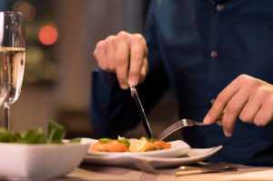 Close up of a male hands cutting and eating delicious salad with