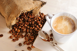 Cup Of Hot Coffee On Table And Sack With Coffee Beans Closeup