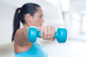 A hand holding blue dumbbell for tricep extension of sporty lady