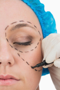 Plastic surgeon writing in the woman face in the white backgroun
