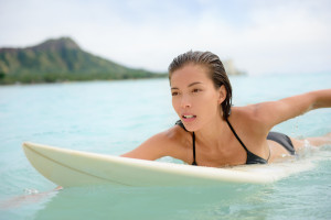 Surfing surfer girl paddle for surf on surfboard. Female bikini