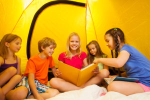 Five funny kids read book in a tent